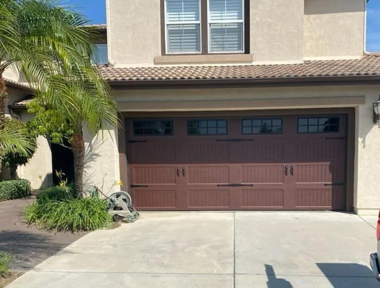 Brown carriage-house garage door with top windows on a stucco home in Ontario, CA