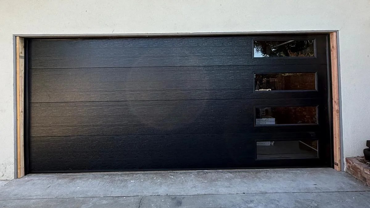 Black modern flush garage door with stacked windows on a stucco Ontario home